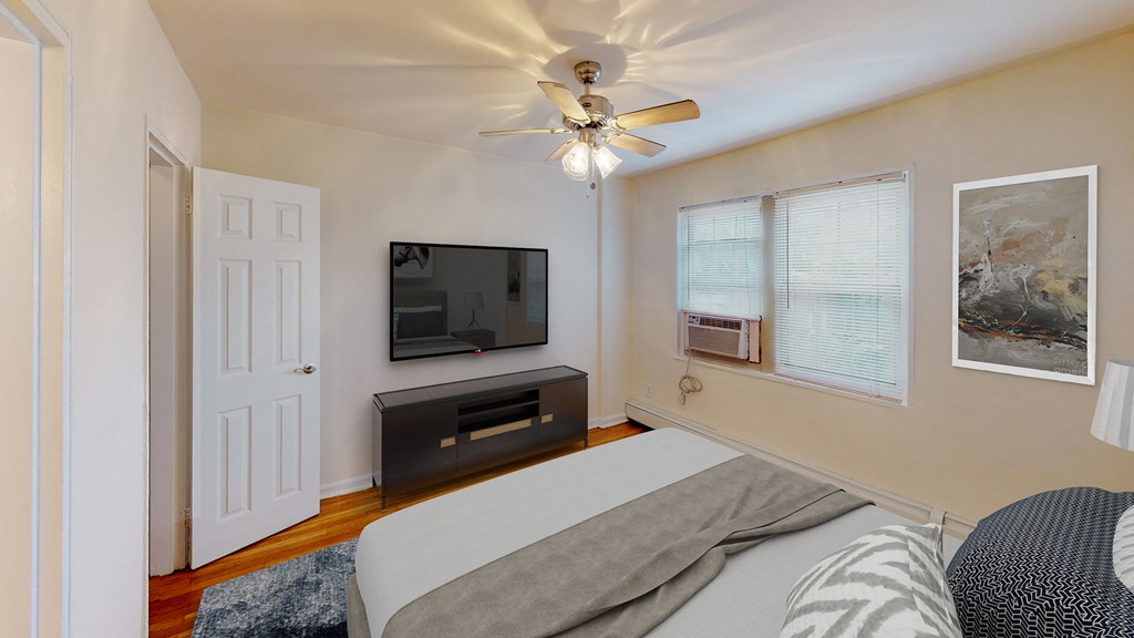 bedroom with bed, nightstands, dresser, tv, ceiling fan and large windows at alpha house apartments in washington dc