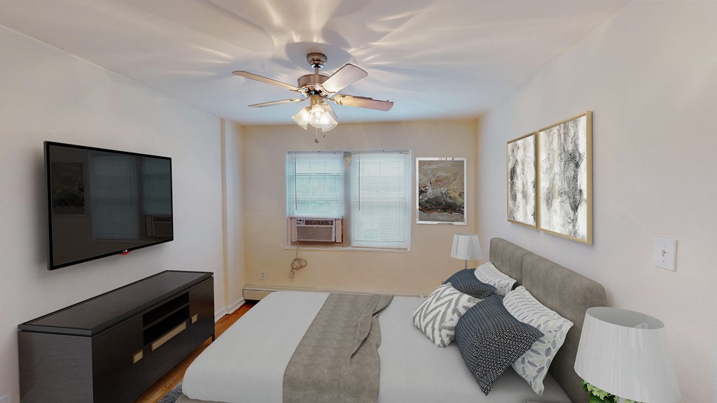 bedroom with bed, nightstands, dresser, tv, ceiling fans and large windows at alpha house apartments in washington dc