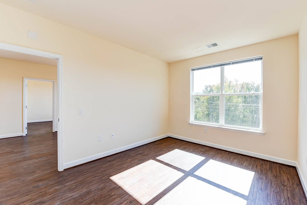 vacant living area with hardwood flooring and large windows at archer park apartments in washington dc