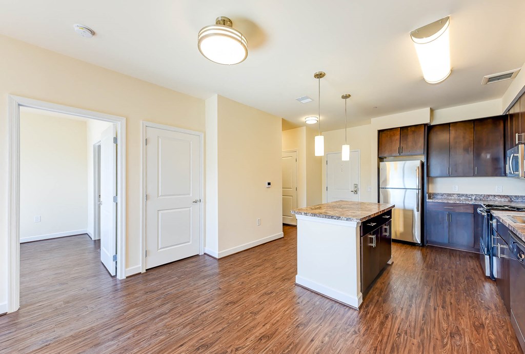 vacant living area with hardwood floors, view of kitchen with stainless steel appliances and kitchen island at archer park apartments in southeast Washington dc