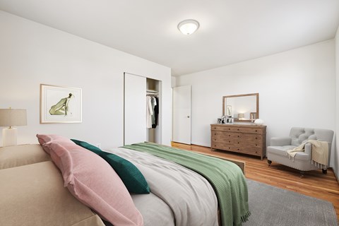 A bedroom with a bed, a dresser, a chair, and a painting on the wall.