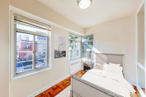 bedroom with bed night stand, hardwood flooring and large windows at baystate apartments washington dc