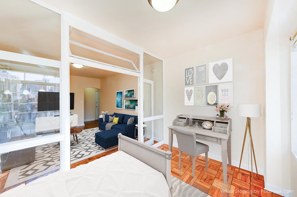 bedroom with bed, desk, hardwood flooring, large windows and a view of living area at baystate apartments washington dc