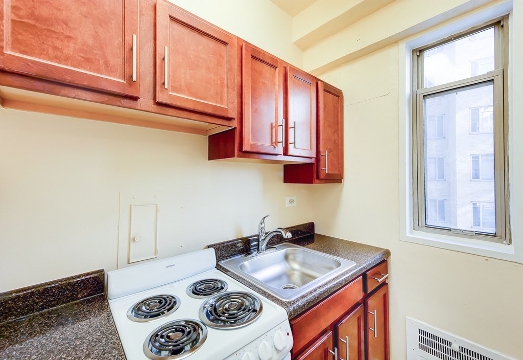 kitchen with window, wood cabinetry and electric range at baystate apartments in washington dc