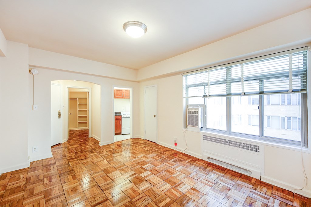 vacant living area with hardwood flooring and large windows at baystate apartments in washington dc