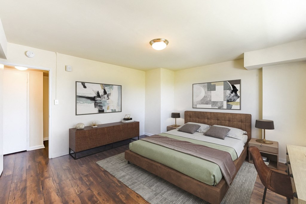 a bedroom with white walls and wood floors and a bed
