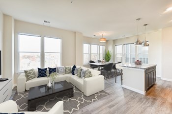 living area with sofa, coffee table , large windows, view of kitchen and view of dining area at city view apartments in washington dc - Photo Gallery 5