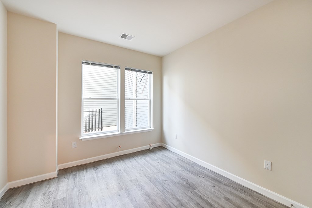 vacant bedroom with hardwood flooring and large windows at city view apartments in washington dc