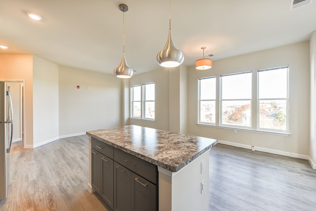 view of kitchen with island and vacant living area with large windows and hardwood floors at city view apartments in washington dc