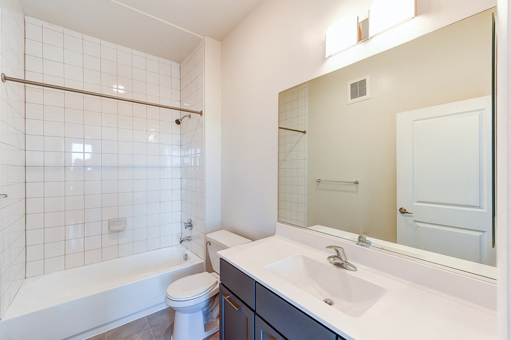 bathroom with large mirror, tub, toilet and vanity at city view apartments in washington dc