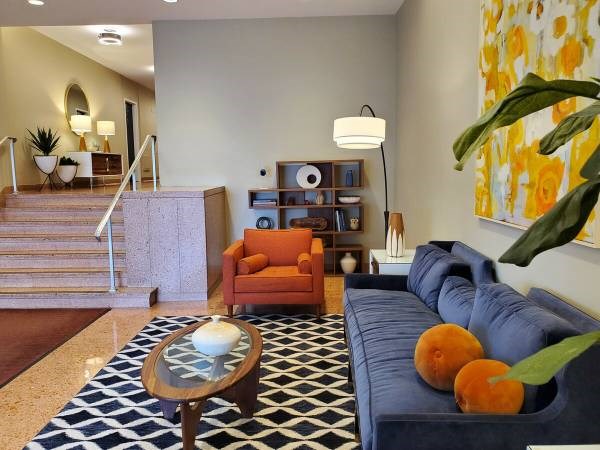 A living room with a blue couch, orange chair, and a coffee table.