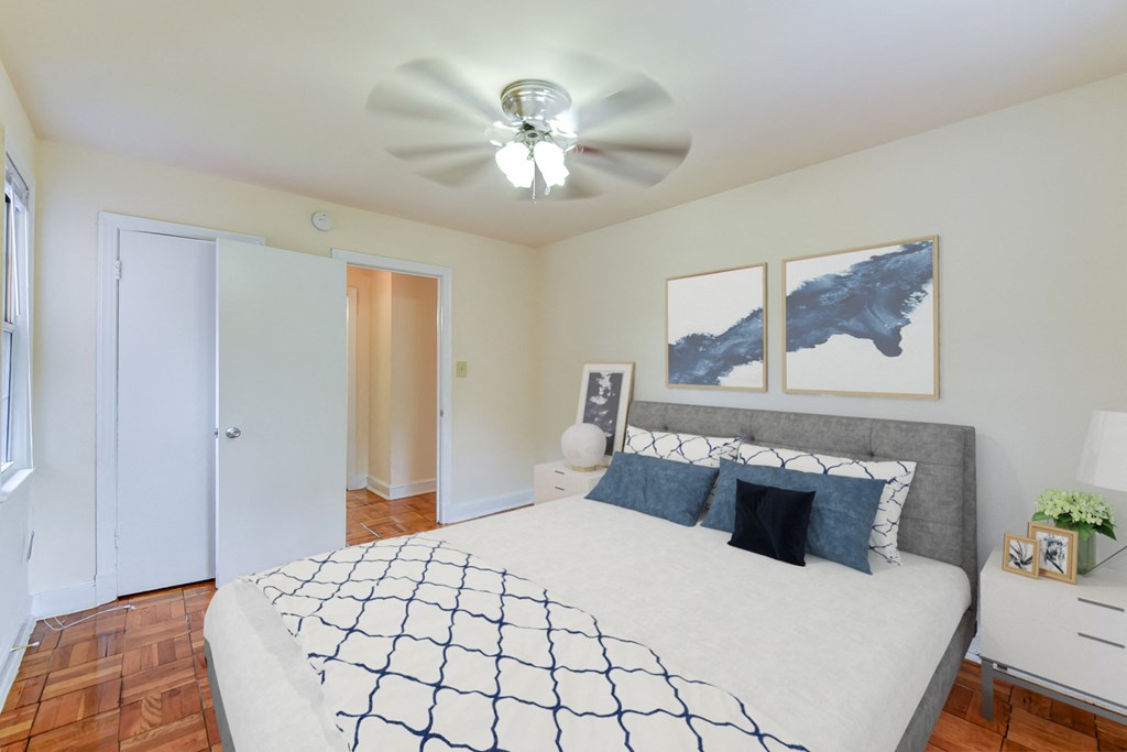Bedroom with bed, nightstands, ceiling fan and hardwood floors at colonnade apartments in washington dc