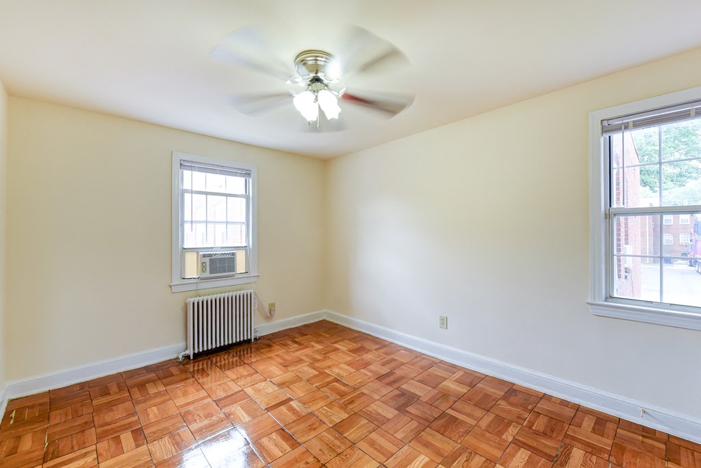 vacant bedroom with hardwood flooring and ceiling fan at colonnade apartments in washington dc