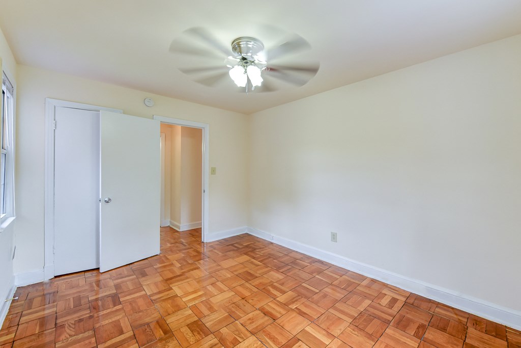 vacant bedroom with hardwood flooring and ceiling fan at colonnade apartments in washington dc