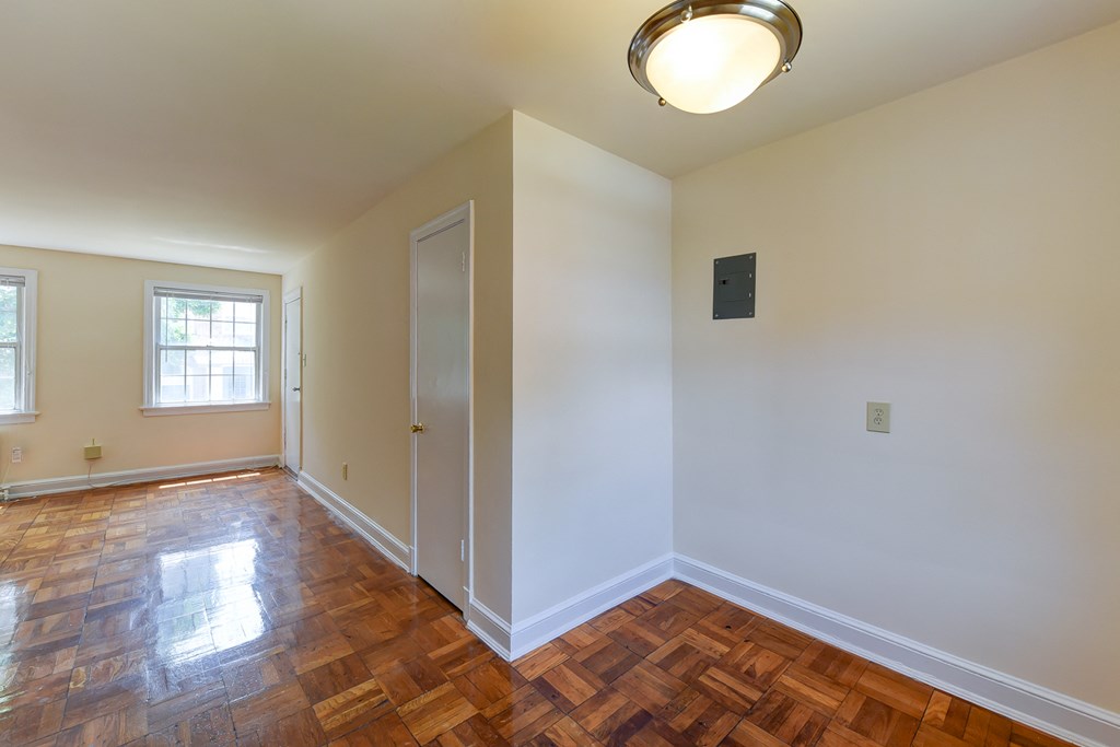 vacant dining area with view of living area with hardwood floors and large windows atcolonnade apartments in washington dc