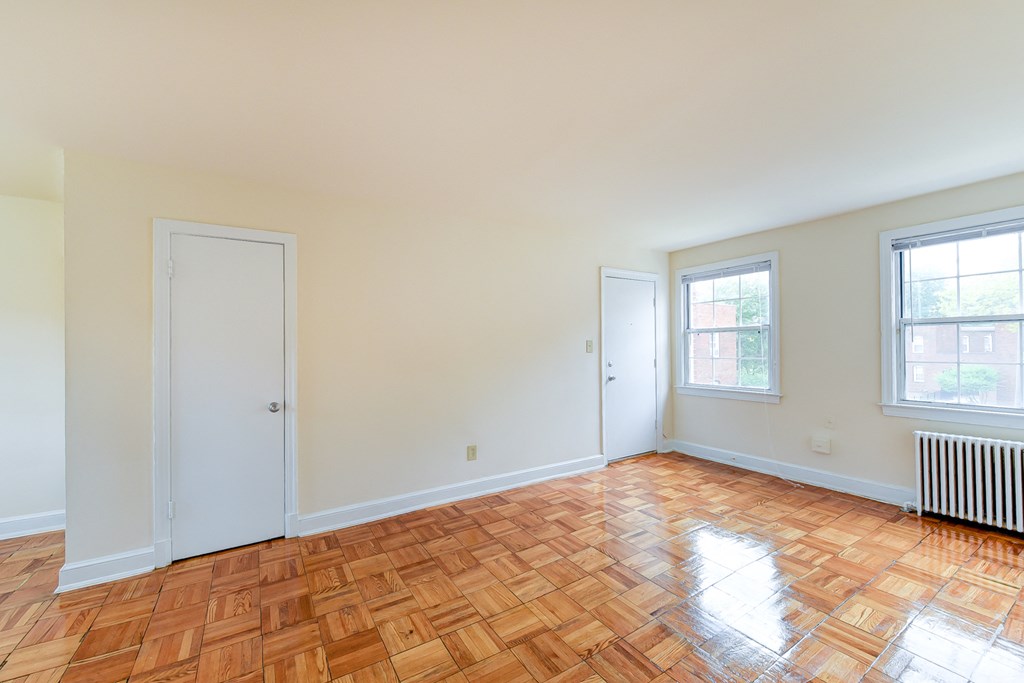 vacant living area with hardwood flooring and large windows at colonnade apartments in washington dc