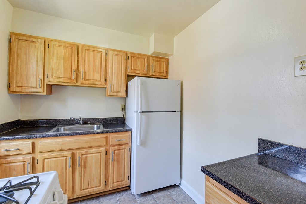 kitchen with wood cabinetry and white appliances at colonnade apartments in washington dc