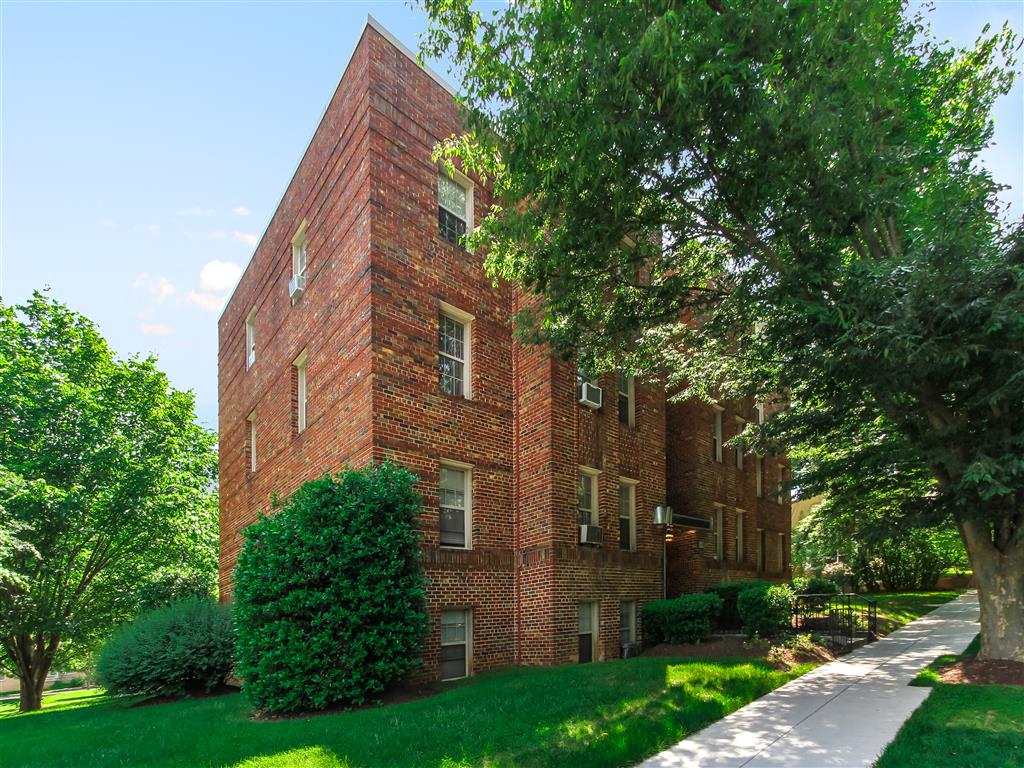exterior of 1400 van buren apartments with lush landscaping, brick building and sidewalk