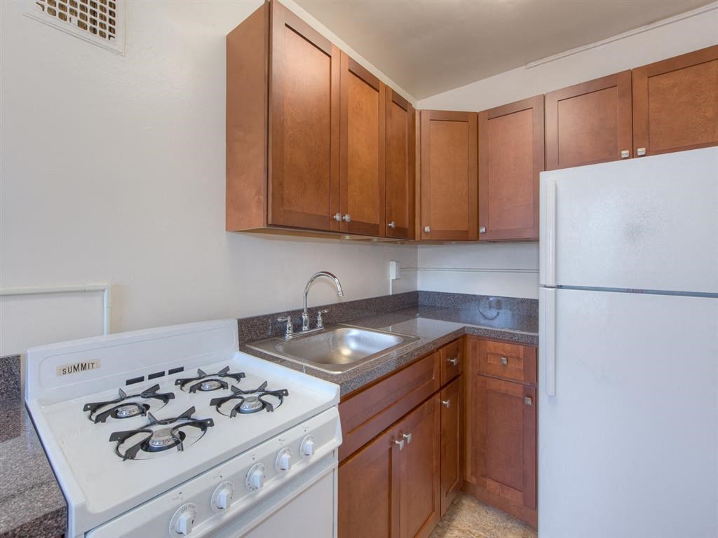kitchen with refrigerator, gas range and tile flooring at 6100 14th Street apartments in washington dc