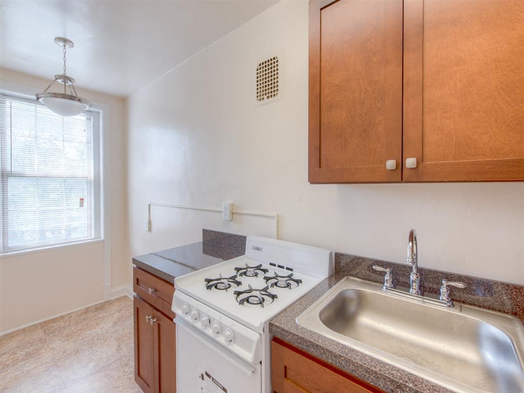 kitchen with gas range, large window and view of dining area at 6100 14th Street apartments in washington dc