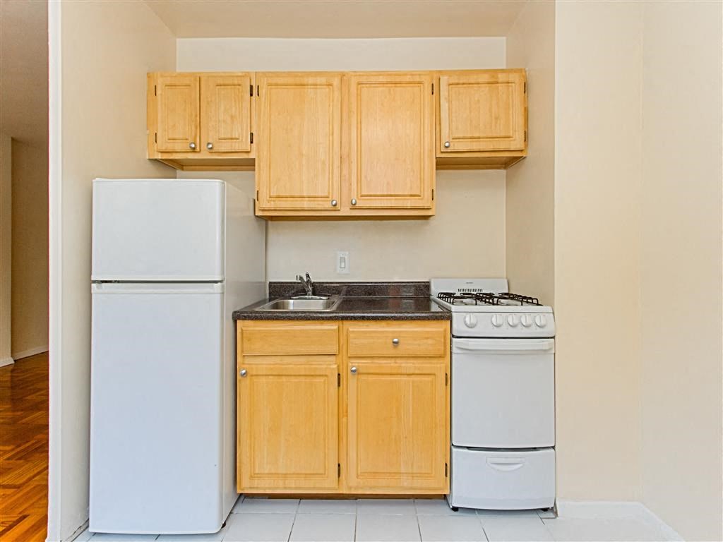 kitchen with light oak cabinetry, stove, refrigerator and sink at brunswick house apartments in dupont circle washington dc
