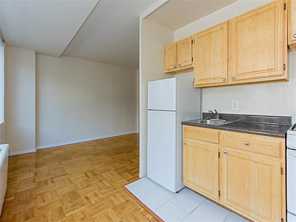 kitchen with light oak cabinetry, stove, refrigerator, sink, and view of living area at brunswick house apartments in dupont circle washington dc