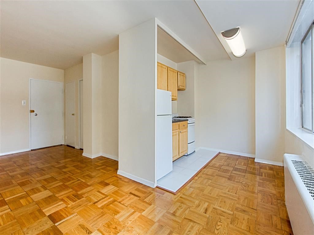 vacant living area with hardwood flooring, view of front entrance and kitchen at brunswick house apartments in dupont circle washington dc