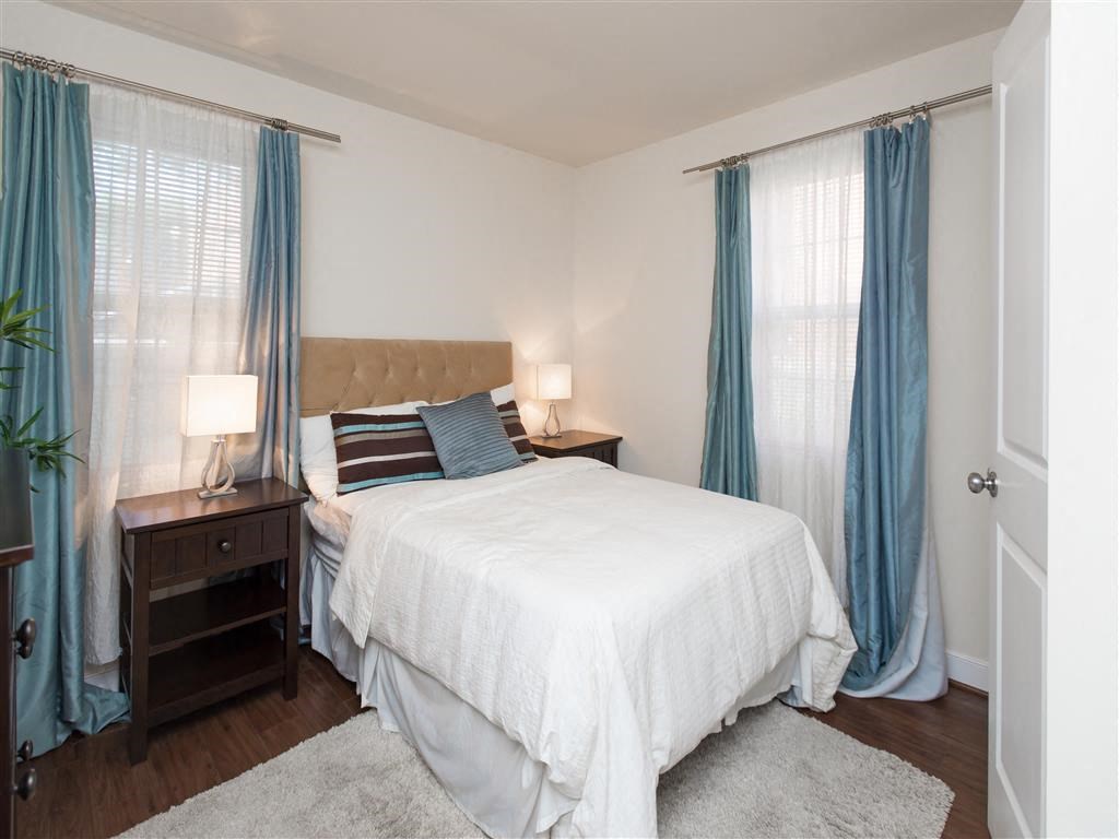 bedroom with bed, nightstands and large windows at fairway park apartments in washington dc