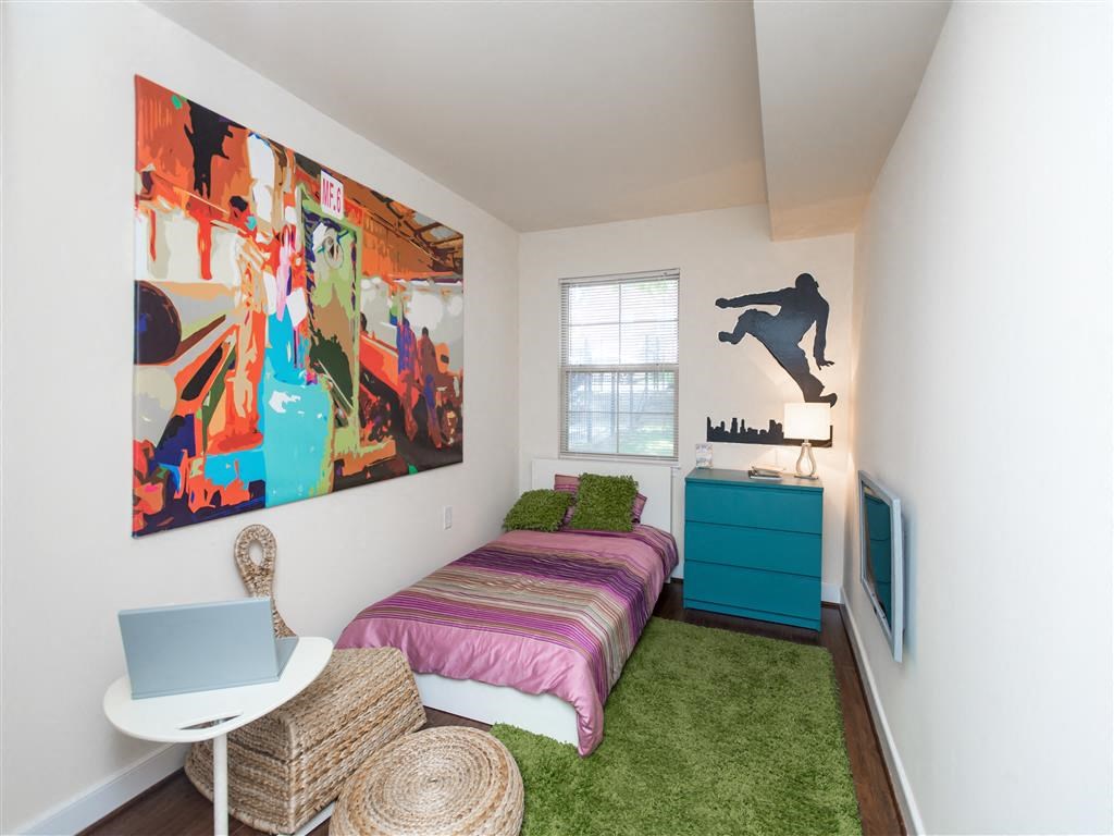 small bedroom with bed, dresser, desk and window at fairway park apartments in washington dc