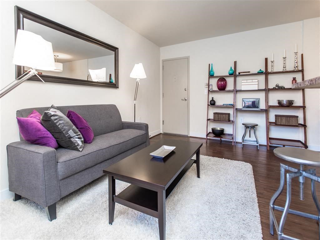 living area with sofa, coffee table, bookshelves, large mirror and view of front entrance at fairway park apartments in washington dc
