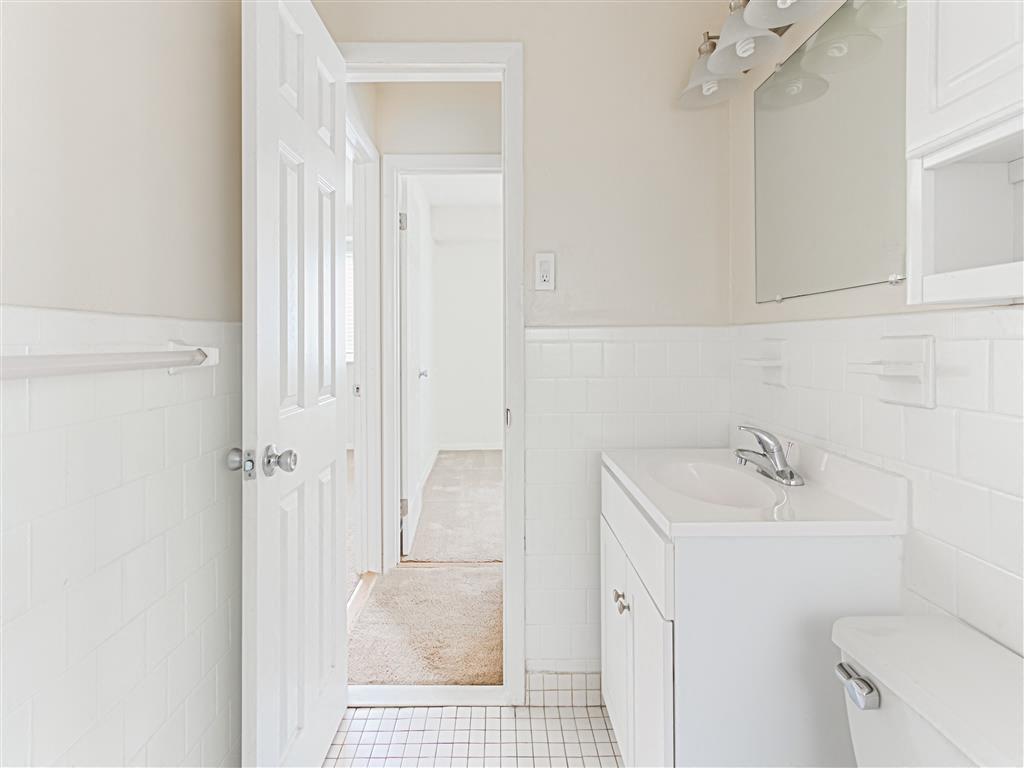 bathroom with white toilet, vanity, large mirror and cabinetry at halley house apartments in washington dc