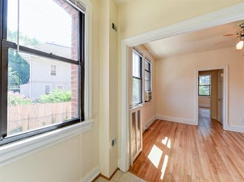 vacant living area with hardwood flooring and large windows at the klingle apartments in washignton dc - Photo Gallery 19