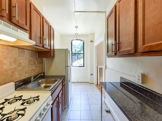 kitchen with wood cabinetry and tile backsplash at the klingle apartments in washignton dc