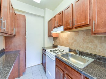 kitchen with wood cabinetry and tile backsplash at the klingle apartments in washignton dc - Photo Gallery 2