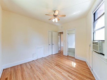 vacant bedroom with hardwood flooring , closet, ceiling fan and view of bathroom at the klingle apartments in washignton dc - Photo Gallery 21