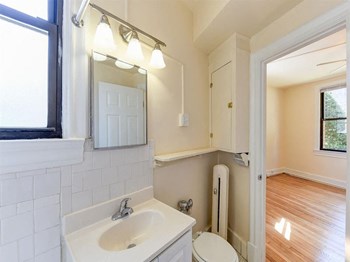 bathroom with vanity, mirror, toilet and view of bedroom at the klingle apartments in washignton dc - Photo Gallery 10
