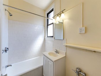 bathroom with tub, vanity, mirror and window at the klingle apartments in washignton dc - Photo Gallery 9
