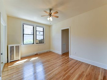 vacant living area with hardwood flooring, large windows and ceiling fan at the klingle apartments in washignton dc - Photo Gallery 14