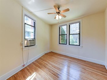 vacant bedroom with hardwood floorings, large windows and ceiling fan at the klingle apartments in washignton dc - Photo Gallery 15