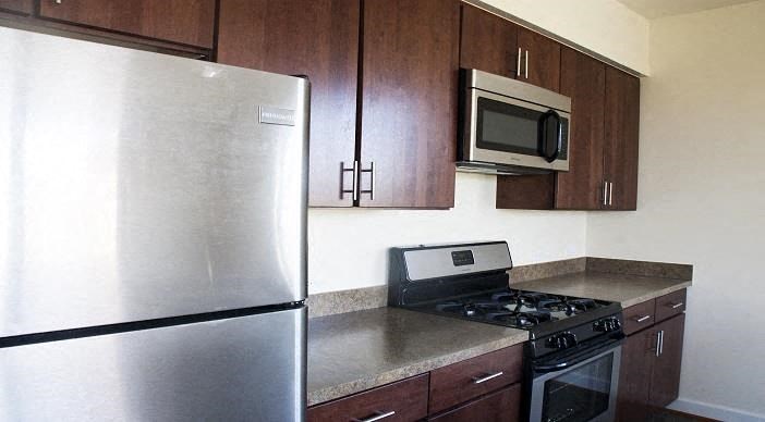 kitchen with espresso cabinetry, stainless steel appliances, and breakfast bar at sheridan station apartments in washington dc