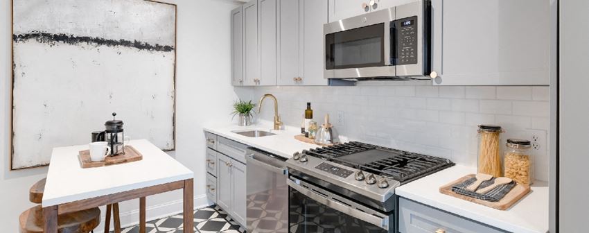 kitchen with white cabinetry, stainless steel appliances, microwave and kitchen island at the dahlia apartments in washington dc - Photo Gallery 1