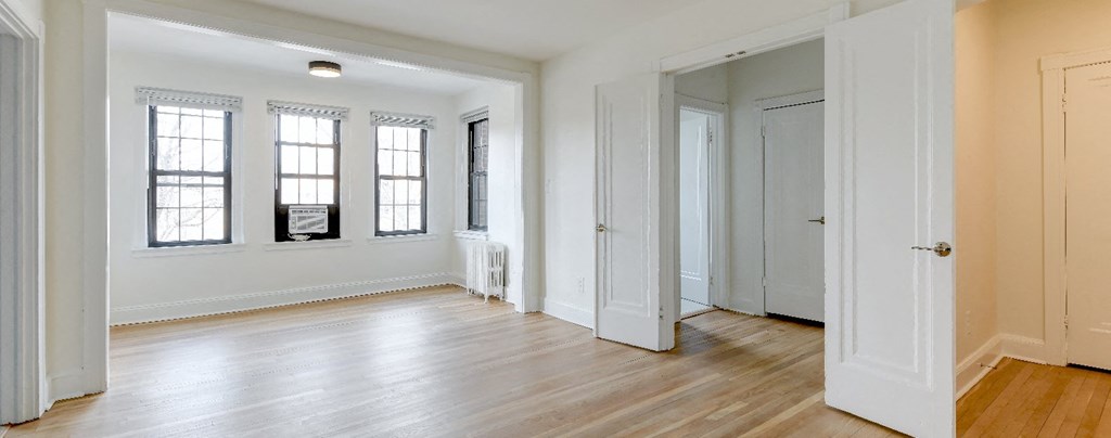 vacant living area with hard wood flooring and large windows at the dahlia apartments washington dc