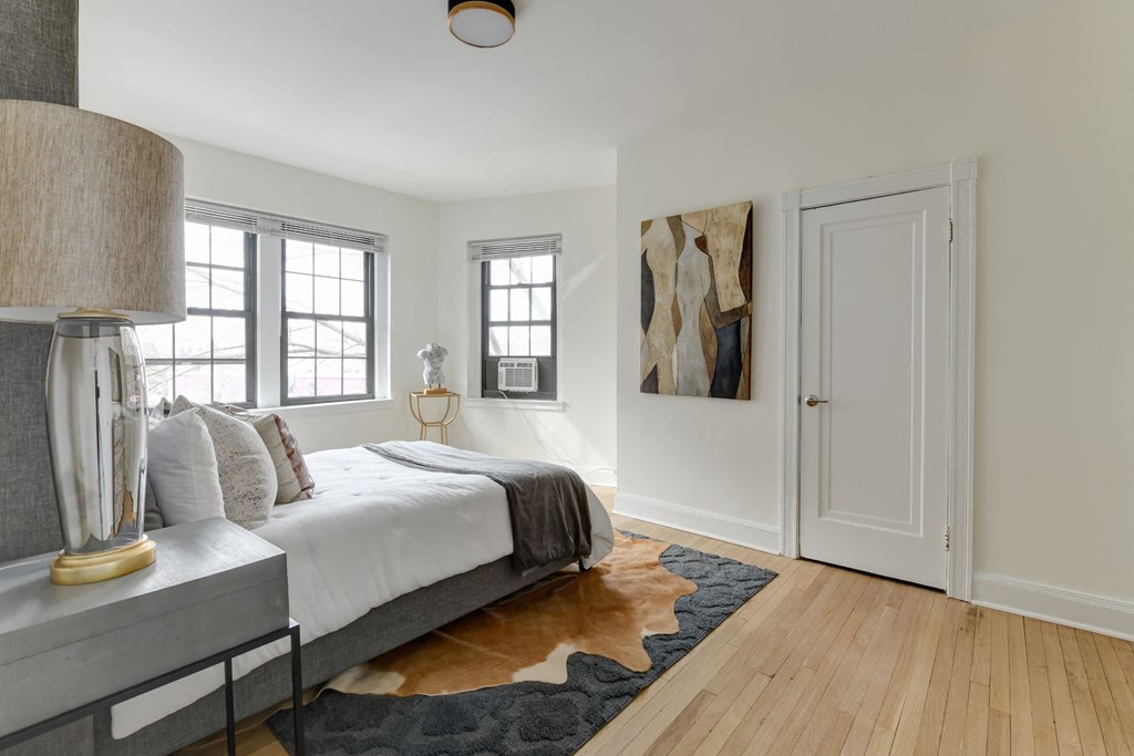 bedroom with bed, nightstands, large windows and  hardwood floors at the dahlia apartments in washington dc