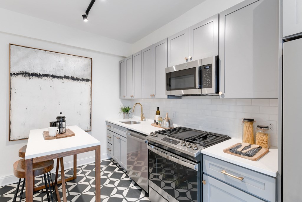 kitchen with white cabinetry, stainless steel appliances, microwave and kitchen island at the dahlia apartments in washington dc