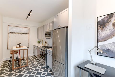 kitchen with white cabinetry, stainless steel appliances, microwave and kitchen island at the dahlia apartments in washington dc