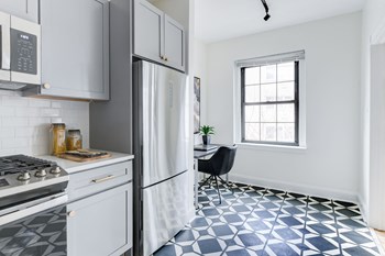 kitchen with white cabinetry, stainless steel appliances, microwave and built in desk at the dahlia apartments in washington dc