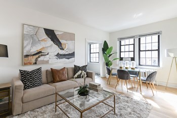 living area with large windows, sofa, coffee table, hardwood floors and view of dining area at the dahlia apartments in washington dc - Photo Gallery 8