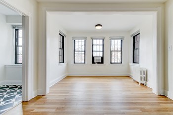 vacant living area with hard wood flooring and large windows at the dahlia apartments washington dc - Photo Gallery 21