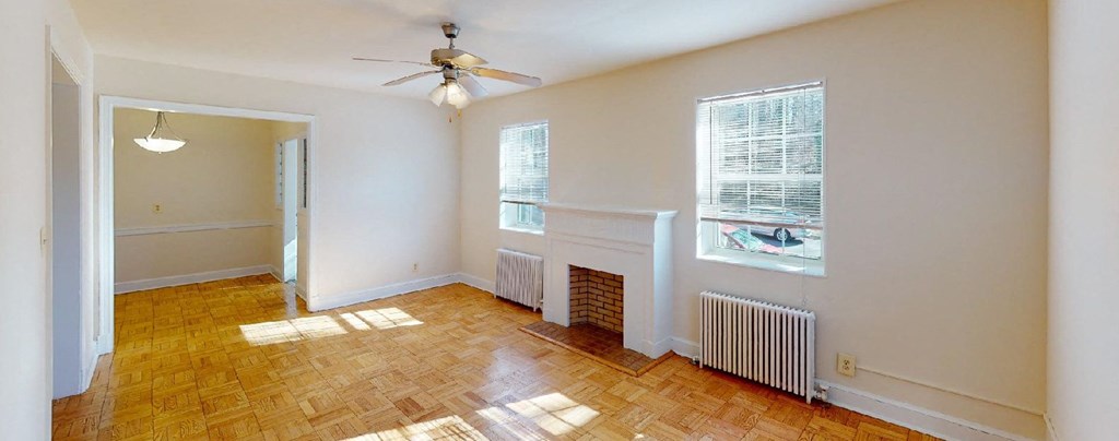 vacant living area with large windows, firelplace and ceiling fan at 4031 davis apartments in washington dc
