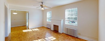 vacant living area with large windows, firelplace and ceiling fan at 4031 davis apartments in washington dc - Photo Gallery 10